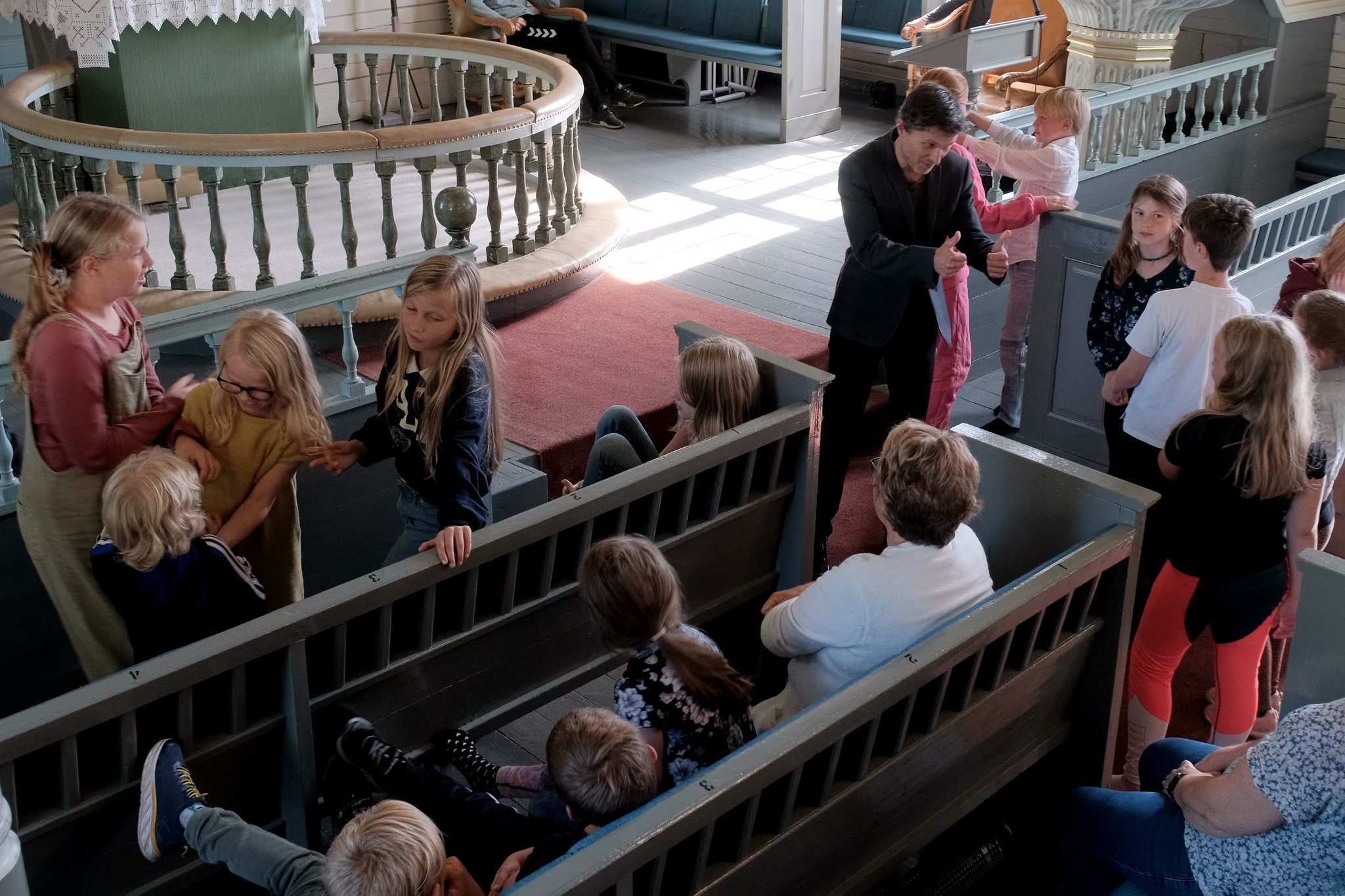 Eit bilete av masse barn i Klepp kyrkje, der presten gir tommel opp til barna