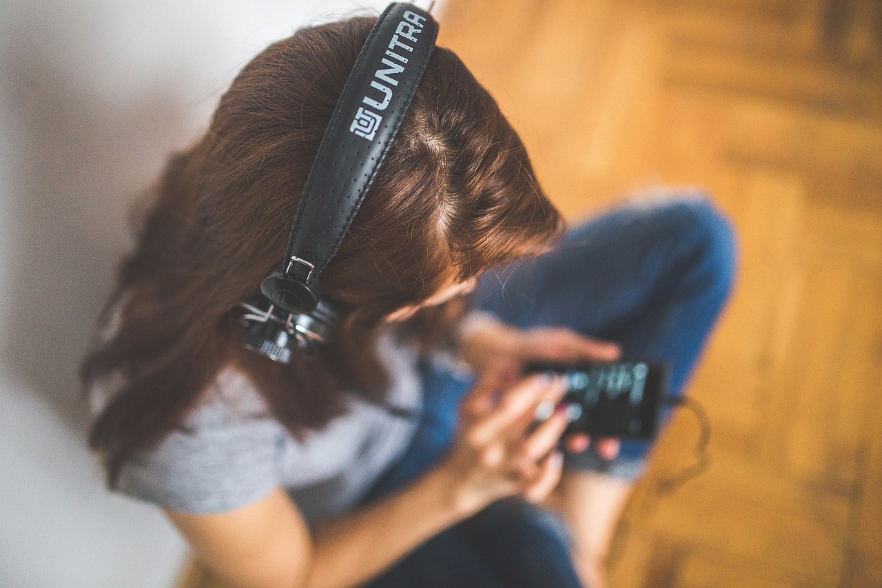 Bilete av ein ungdom som sit på golvet og høyra på musikk på telefonen sin